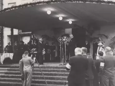 Prezident Edvard Beneš poslouchá na tribuně postavené před vchodem do Městského divadla 22. srpna 1937 projev starosty města Olomouce JUDr. Richarda Fischera. Fotodílna Jana Oto Voleníka. Státní okresní archiv v Olomouci, Sbírka obrazového materiálu a fotografií M 8-34, inv. č. 2267. <a href='http://vademecum.archives.cz/vademecum/permalink?xid=8D4A3D0470C94A358DB2979D8BD153BD&scan=1' target='_blank'>Digitalizát</a>