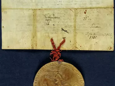 Státní okresní archiv v Olomouci, Archiv města Olomouce, fond M-1-1, Listiny, inv. č. 10, pergamen, 26,5 × 16,5 cm, plika o šířce 4 cm, majestátní mincovní pečeť, přivěšená na červených a modrých hedvábných nitích, je v plechovém pouzdře.